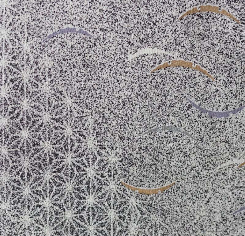 黒地に白い砂子状の点描が一面に広がり、麻の葉文様と曲線の刺繍を配した着物生地のクローズアップ。橙・紫・銀の弧が点在する構図。