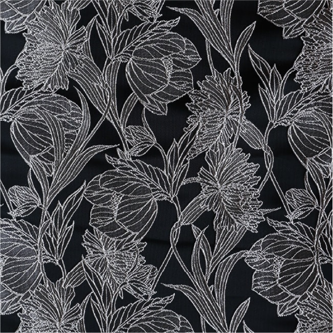 黒地に白い線で大きな花と葉を描いた着物生地のクローズアップ。花弁や葉脈が細い銀糸風の線で表現され、全面に密に配された植物文様。